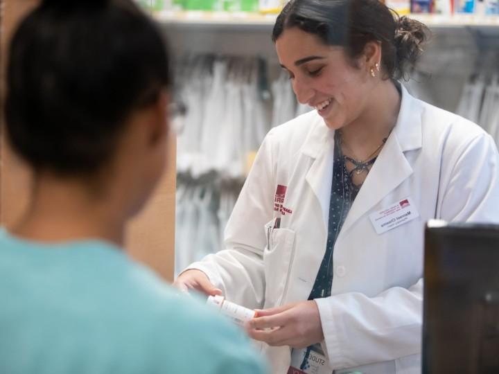 A student works in student operated pharmacy with patient